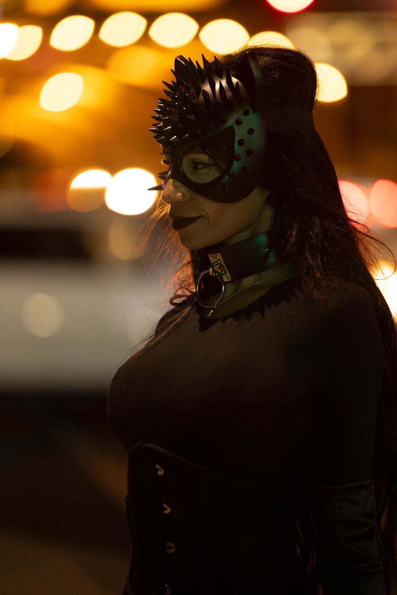 Illustrative stock photograph of an adult in a black mask with warm city lights, not a real member from the UK